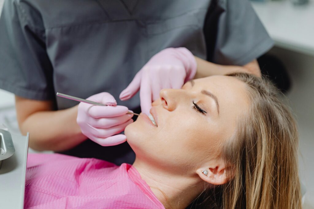 Smiling dentist examining patient's teeth during check-up